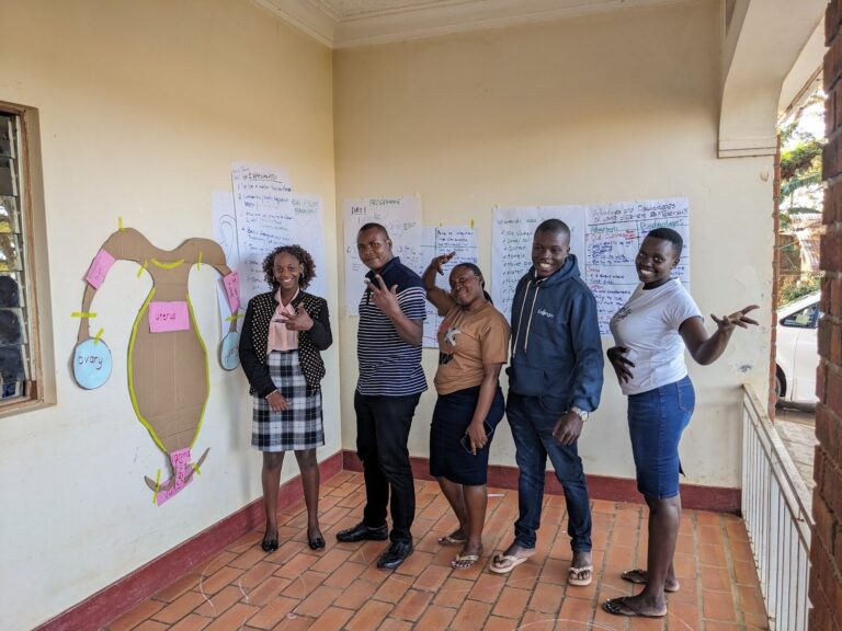Participants beside a reproductive health teaching chart